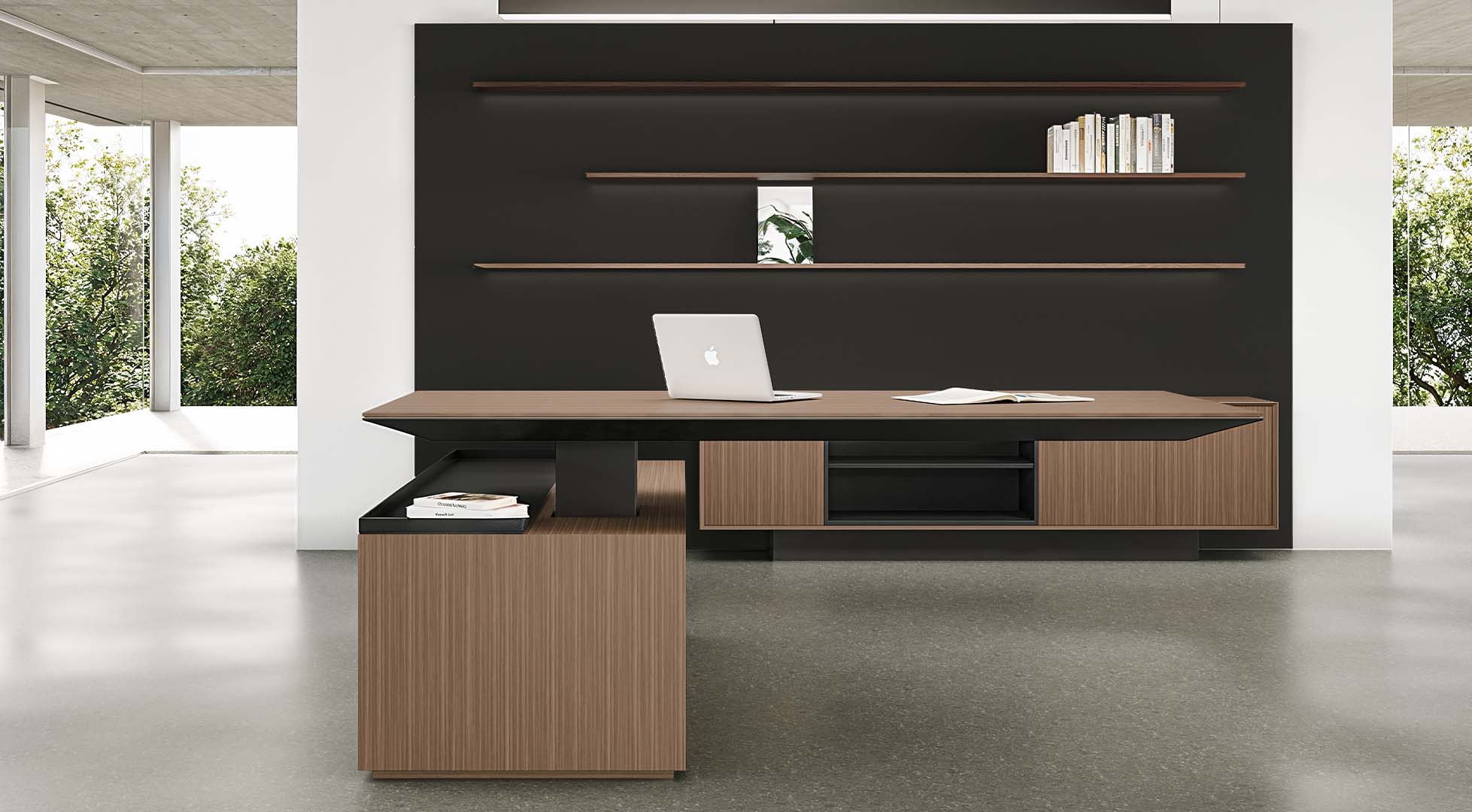 Contemporary executive desk featuring a rich wood grain top, integrated black storage credenza, and a large supporting cabinet with a pull-out tray, set against a dark feature wall with floating shelves.
